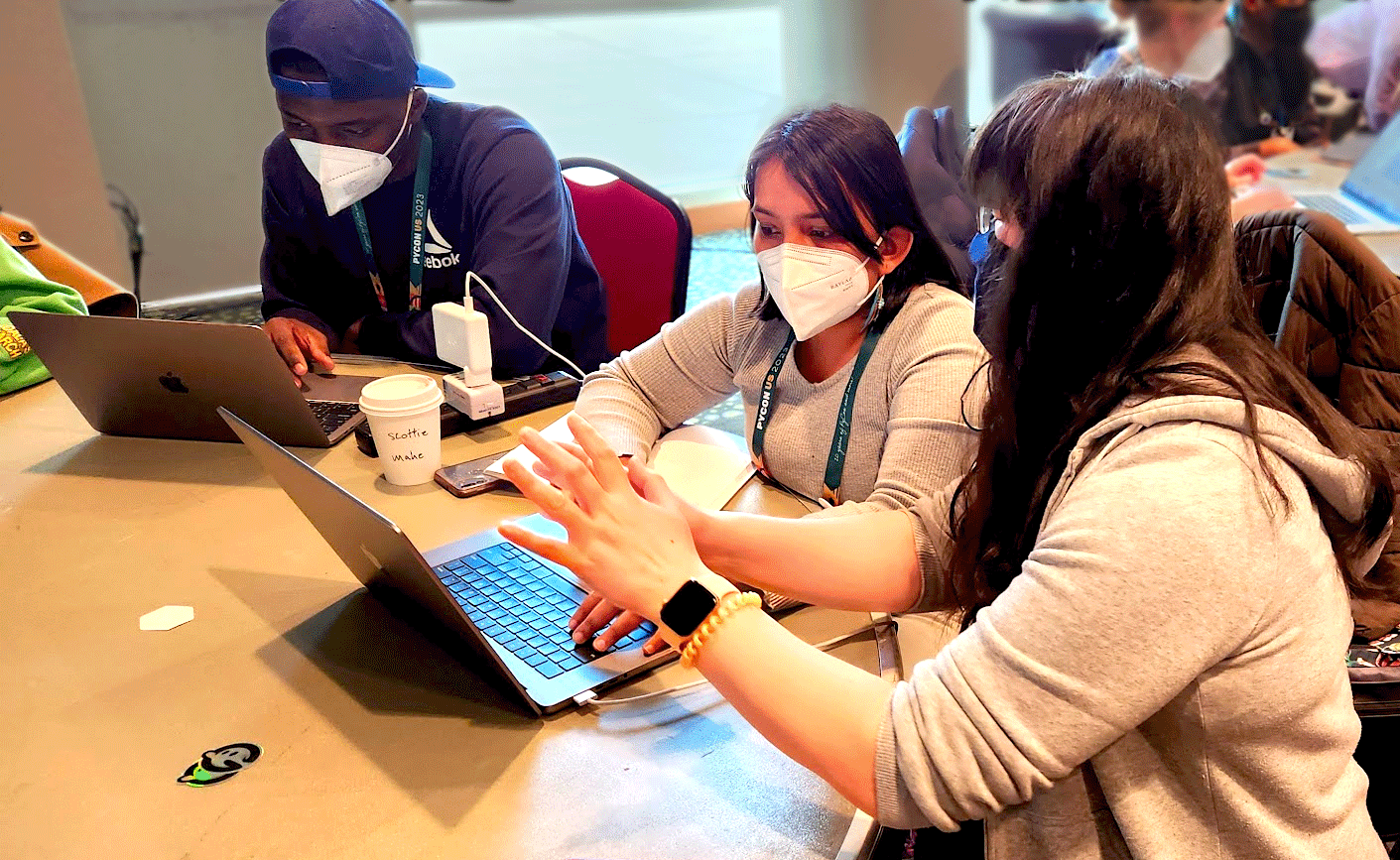 Three people working at two computers during a PyCon USA sprint in 2023.